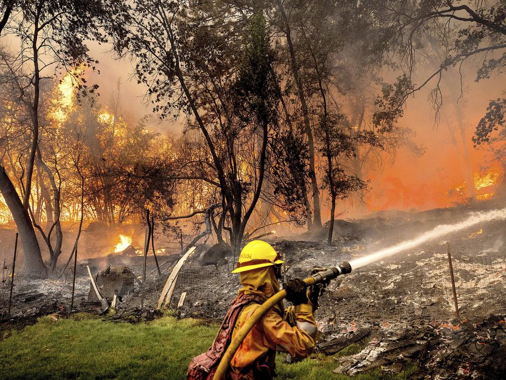 Firefighter Christian Moorhouse battles the Park Fire tears through the Cohasset community in Butte County, Calif., on Thursday, July 25, 2024. His crew was able to keep flames from reaching the mobile home they were protecting.