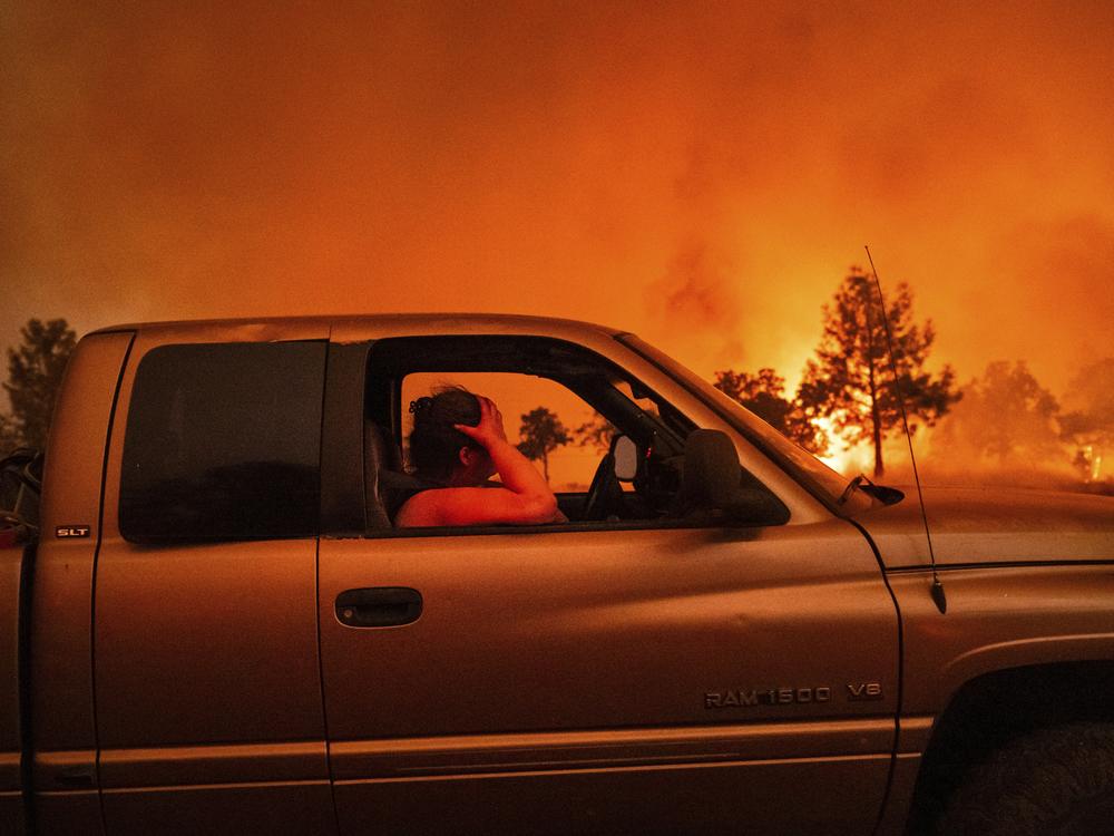 Andrea Douglas holds her head while evacuating as the Park Fire jumps Highway 36 near Paynes Creek in Tehama County, Calif., on Friday.
