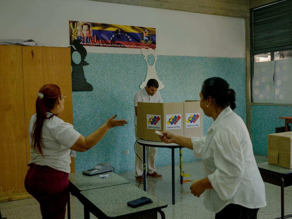 Election workers clap as the final person in the line votes at the Cristo Rey school voting center in Caracas' Altamira neighborhood on Sunday afternoon. Those in line for Table 11 had been waiting since 6 a.m. to vote and, due to technical error with the voting machine, were drastically delayed.