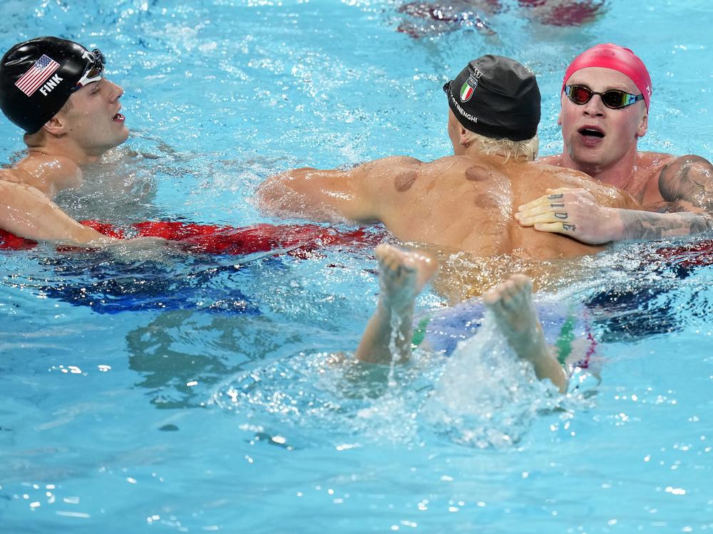 Nicolo Martinenghi, center, of Italy, is congratulated by Adam Peaty, of Great Britain, right, and Nic Fink, of the United States, left, after winning the men's 100-meter breaststroke final at the 2024 Summer Olympics on Sunday.