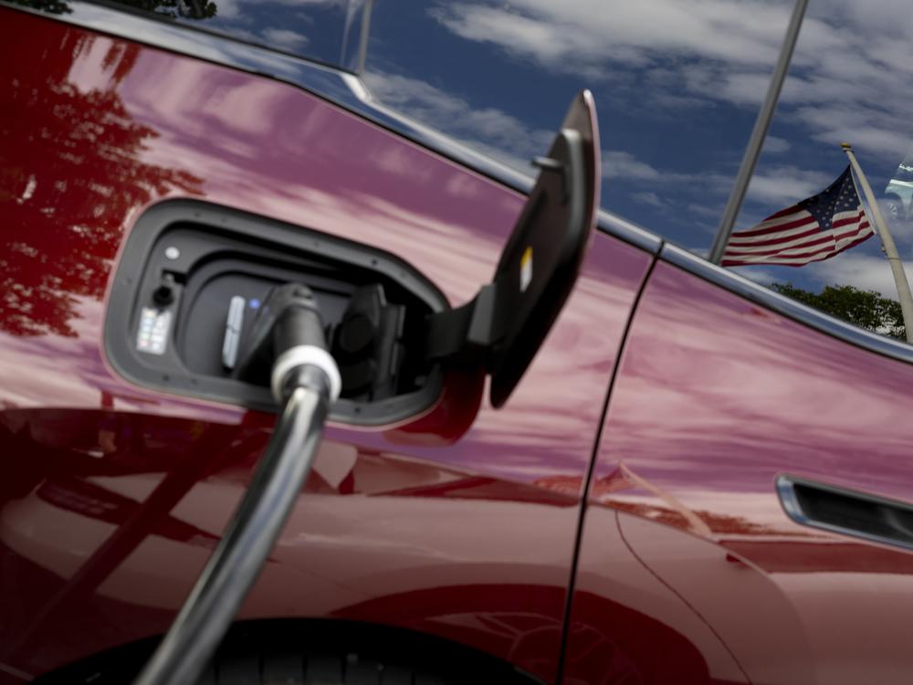 An American flag is reflected in the window of an electric car.