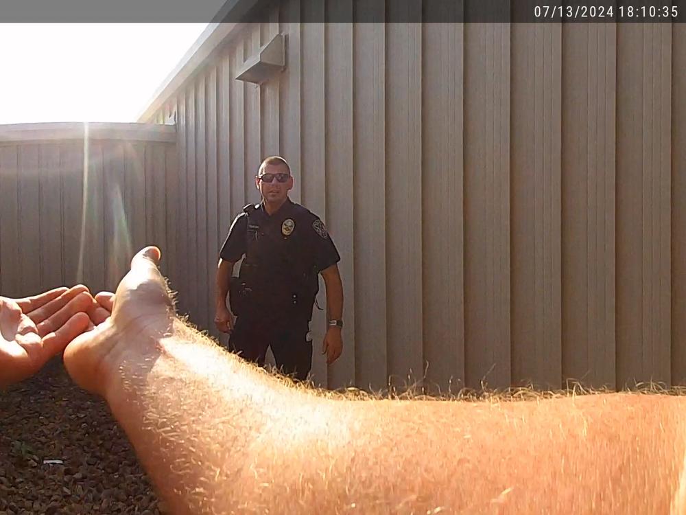  One officer gestures to his colleague to hoist him up so he can gain access to the roof. It's there that he encounters the gunman.