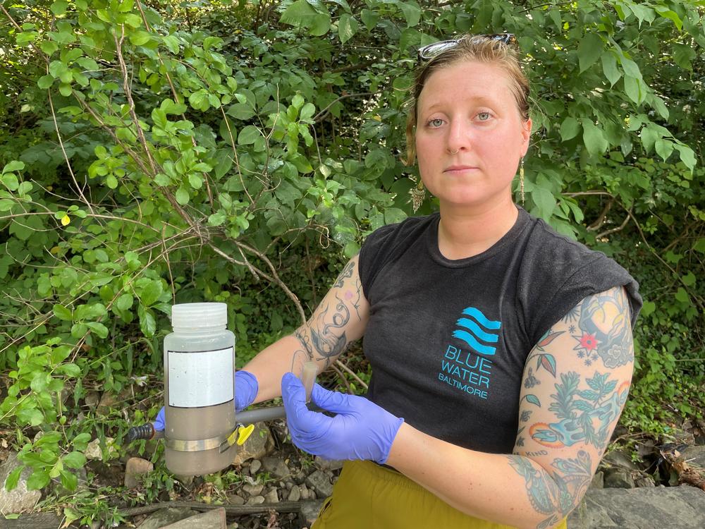  Sarah Holter of Blue Water Baltimore holds a sample of polluted water seen running into the Jones Falls in Baltimore.