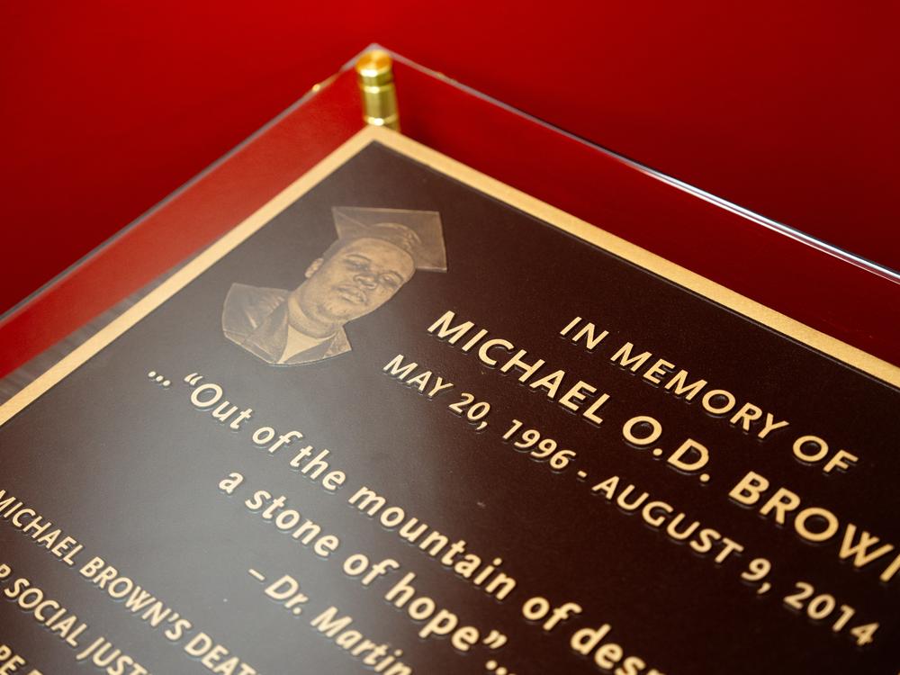 A memorial plaque sits next to a phone booth art piece on Tuesday, Aug. 6, 2024, at the Ferguson Empowerment Center in Ferguson.