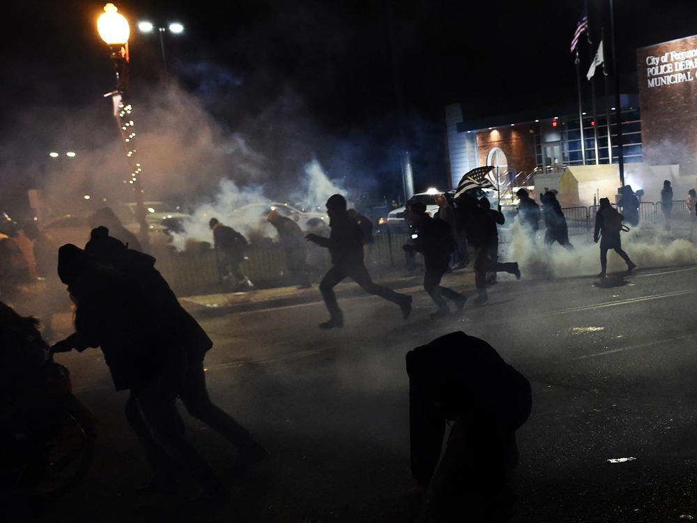 Demonstrators flee as police fire tear gas during clashes following the grand jury decision in the death of 18-year-old Michael Brown in Ferguson, Missouri, on November 24, 2014. 