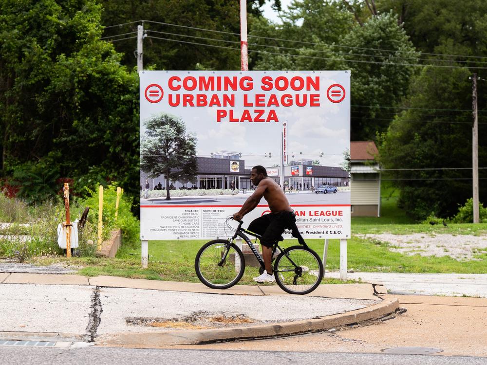 A pedestrian rides by the future home of the Urban League Plaza on Friday, Aug. 2, 2024, in Ferguson.