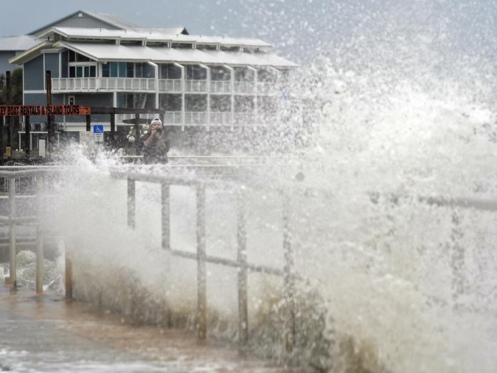 Surf from Tropical Storm Debby breaks over a sea wall in Cedar Key, Fla., in August 2024. Abnormally hot ocean water is contributing to a very active Atlantic Hurricane season. Climate change is the main driver of record-breaking ocean temperatures, but scientists are trying to figure out what other causes may be at play.