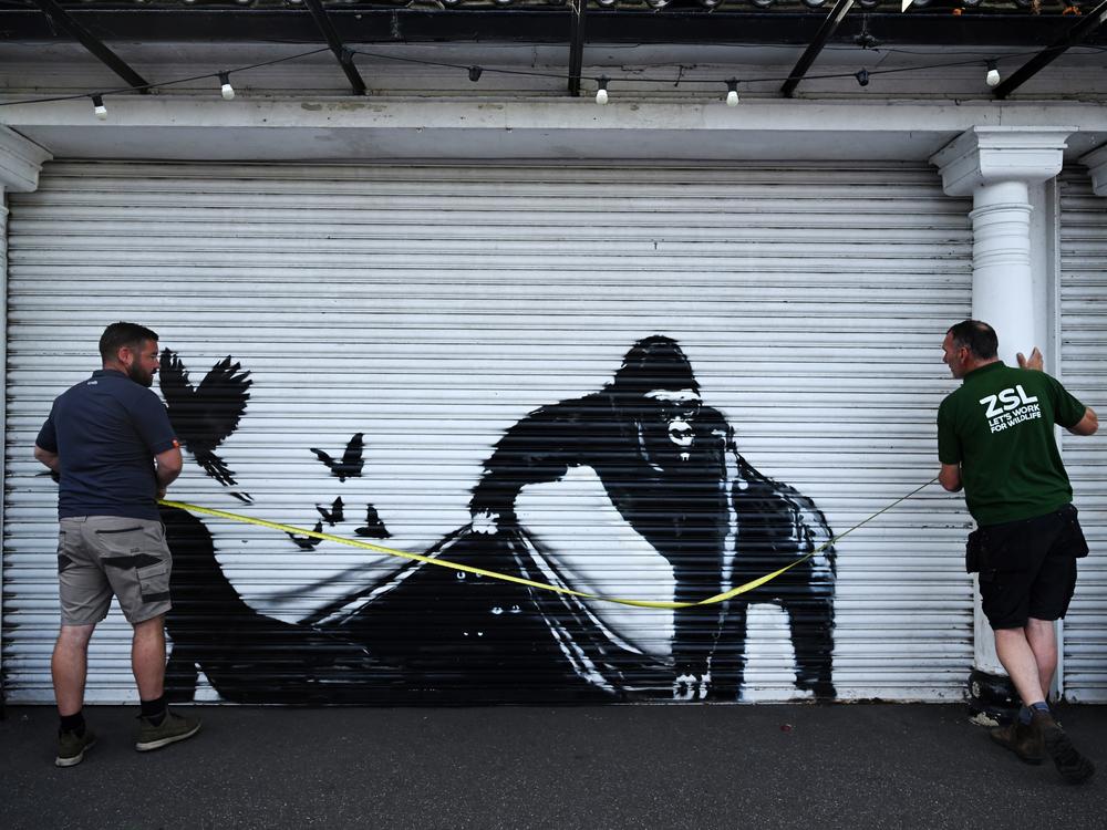 Zoo staff measure up a mural of a gorilla freeing animals that adorns a shutter at the London Zoo on Aug. 13.