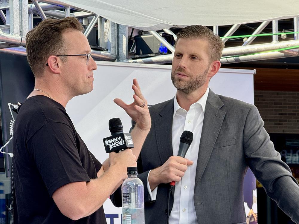 Political commentator and YouTuber Benny Johnson (left) speaks with Eric Trump, a son of former President Donald Trump, during the 2024 Republican National Convention in Milwaukee. Johnson made videos for Tenet Media. The Justice Department accused a company matching Tenet's description of working closely with employees of Russian state broadcaster RT to covertly spread pro-Russian narratives in the United States. Johnson says he was not aware of Tenet's ties to Russia.