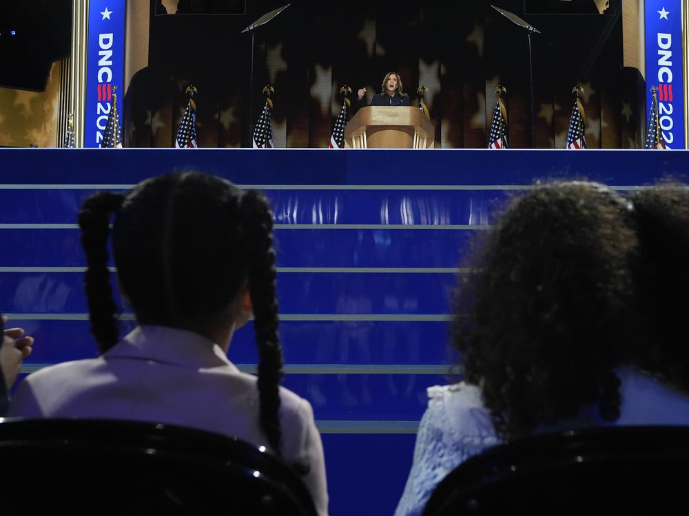 Vice President Kamala Harris speaks as her grand-nieces Amara Ajagu, left, and Leela Ajagu watch during the Democratic National Convention on Aug. 22, 2024, in Chicago.