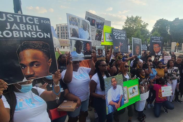 Activists hold signs for families seeking justice in police brutality cases in Atlanta during a May 25, 2021 rally.