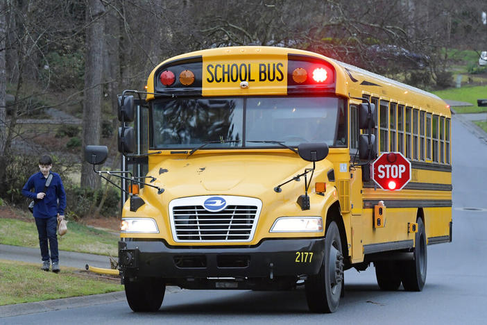 A Cobb County School bus moves on street Friday, March 13, 2020, in Kennesaw, Ga. (AP Photo/Mike Stewart, File)
