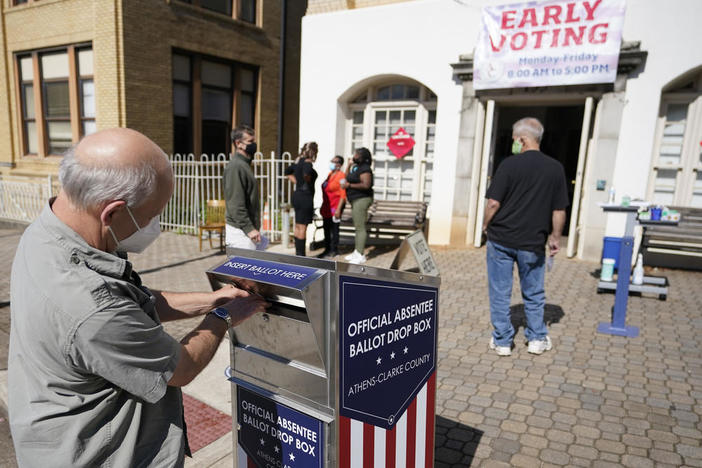 A voter drops their ballot off during early voting, Monday, Oct. 19, 2020, in Athens, Ga. With record turnout expected for this year’s presidential election and fears about exposure to the coronavirus, election officials and advocacy groups have been encouraging people to vote early, either in person or by absentee ballot.