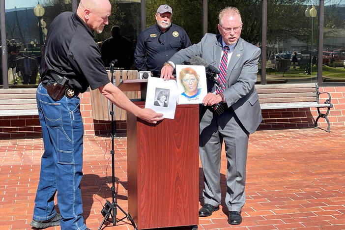 In this photo provided by The Georgia Bureau of Investigation investigators hold a photo of Stacey Lyn Chahorski, left, of Norton Shores, Mich., and a composite sketch of her in Trenton, Ga., March 24, 2022. Georgia and federal officials said on Tuesday, Sept. 6, 2022, that DNA has identified a deceased truck driver as the man who killed the young woman in 1988 in the state's far northwest corner. Officials said genetic genealogy points to Henry Fredrick “Hoss” Wise as the killer of Chahorski. (The Georgia 