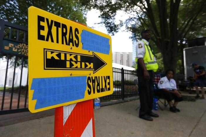 In this Thursday, July 25, 2019 photo, security guards are posted near an entrance to Centennial Olympic Park in downtown Atlanta where a sign for movie extras is set up for Clint Eastwood's film currently titled "Richard Jewell." AP Photo/Andrea Smith