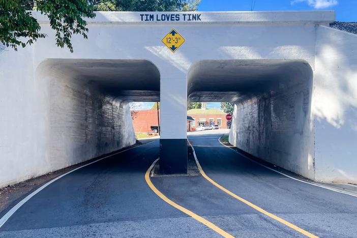A highway underpass is shown.  Stenciled on the underpass is a message: "Tim Loves Tink."