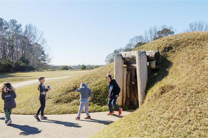 Students leave the Earth lodge, thought to be used historically as a council space, at the Ocmulgee Mounds National Historic Park in Macon in 2022. 