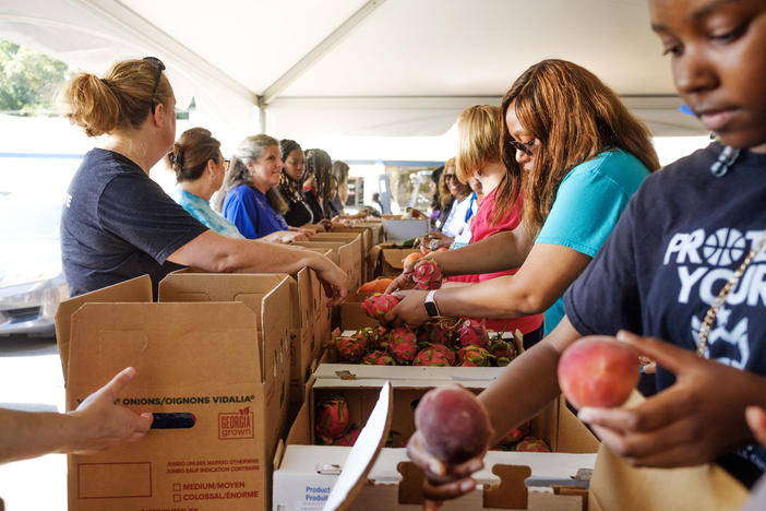 Volunteers pack boxes assembly line style during the annual food distribution in Macon sponsored by Atrium Health. About 60 tons of fresh produce was packed and distributed on a first come, first served basis at the three hour event Friday for which some people arrived two hours early. 