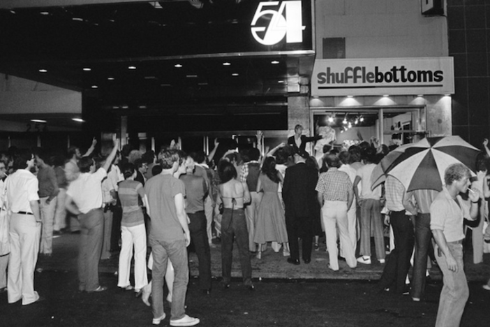 A black and white photo of people standing outside of Studio 54.