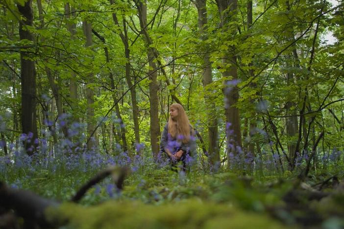 A woman standing in a forest.