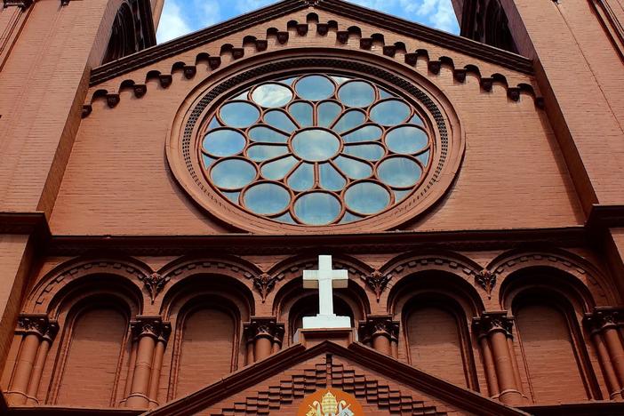 The Basilica of the Sacred of Jesus on Peachtree Street in Downtown Atlanta is known for its twin towers and red brick. Above the entryways is a flat facade with a large rose window that includes a design of the Sacred Heart. (Photo by Dyana Bagby)