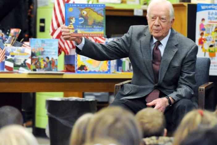 Former President Jimmy Carter holds up a book to elementary schoolchildren