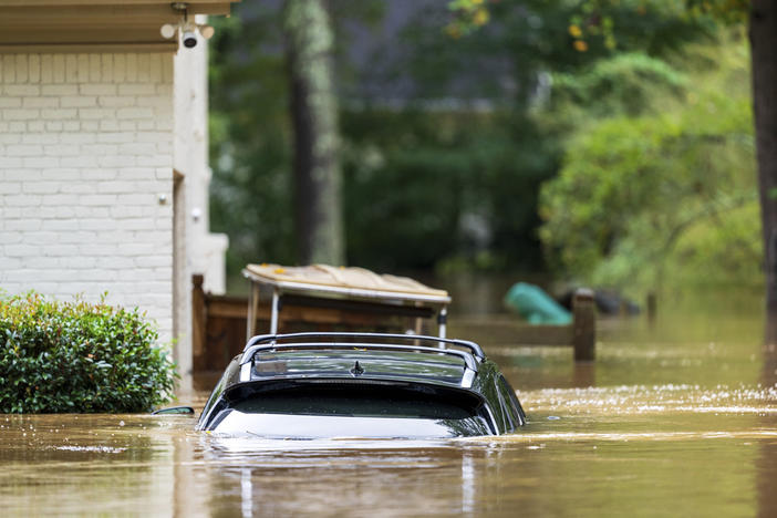 A vehicle is submerged outside a home near Peachtree Creek in Atlanta Friday, Sept. 27, 2024. 