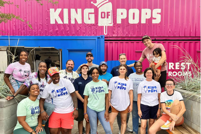 A crew of people wearing King of Pops t-shirts stand in front of a King of Pops storefront.