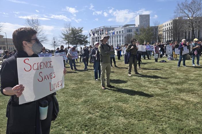 A protester holds a sign: "Science Saves Lives"