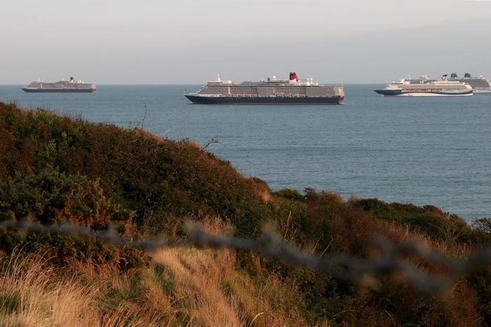Waiting to set sail, idled cruise ships at anchor attract visitors in the UK