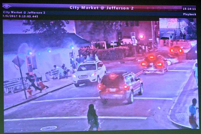 Surveillance video footage shows a white SUV, left, drive slowly past a sidewalk bench where several people in Savannah were gathered before they started running as gunshots were fired.