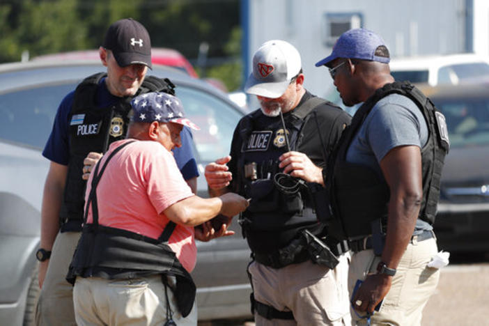 Domingo Candelaria, a registered immigrant, shows federal agents his identification as he prepares to leave the Koch Foods Inc., plant in Morton, Miss., following a raid by U.S. immigration officials, Wednesday, Aug. 7, 2019. 