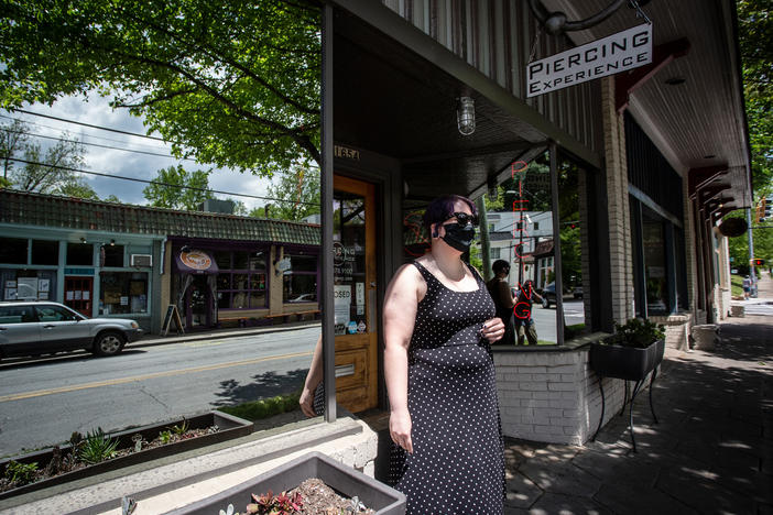 Christina Blossey stands in front of her body piercing business, Piercing Experience, Tuesday, April 21, 2020, in Atlanta. Blossey says her business is likely to remain closed until she can be assured that she can acquire masks and cleaning materials.