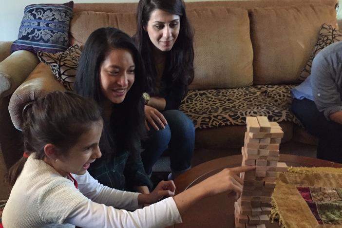 Bee Nguyen (m) works with Syrian refugees adjusting to life in the U.S. She plays a game of Jenga with Nawroz, 10, whose family arrived in Decatur, Georgia earlier this year. Watching on is Kurdeen Karim, who came to Georgia as a refugee in the late '90s.