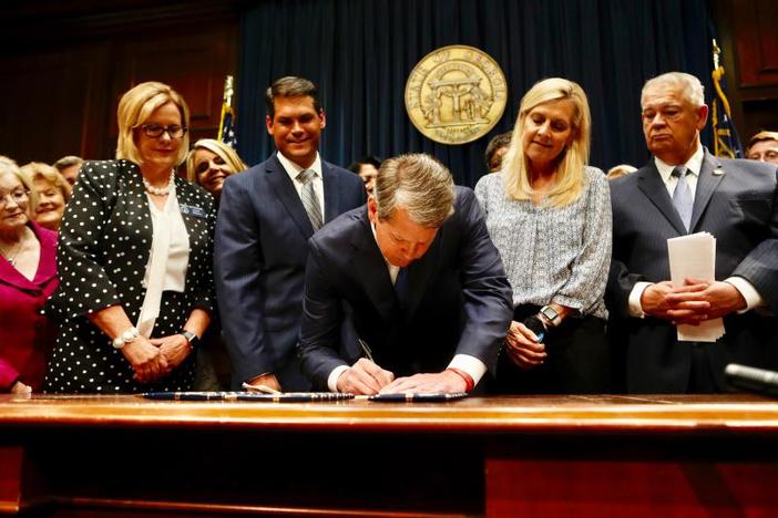 Georgia's Republican Gov. Brian Kemp, center, signs legislation in Atlanta, banning abortions once a fetal heartbeat can be detected, which can be as early as six weeks before many women know they're pregnant. 