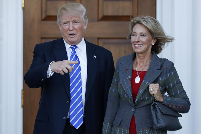 President-elect Donald Trump calls out to the media as he and Betsy DeVos pose for photographs at Trump National Golf Club Bedminster clubhouse in Bedminster, N.J., Saturday, Nov. 19, 2016.