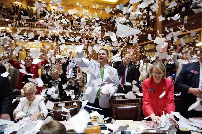 State Rep. Christian Coomer, R-Cartersville, center, and fellow lawmakers throw up paper from their desks at the conclusion of the legislative session in the House chamber, in Atlanta, Friday, March 31, 2017. 