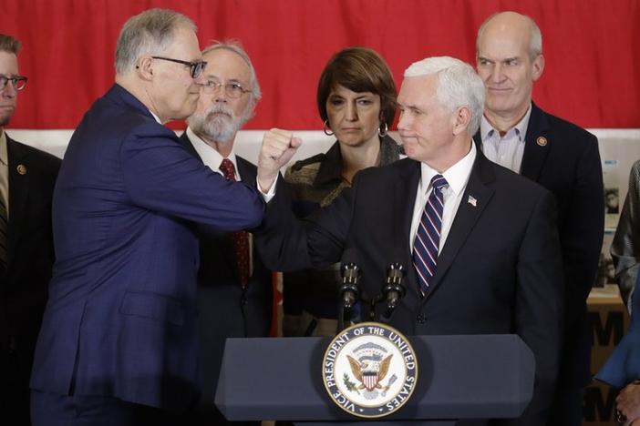 Vice President Mike Pence bumps elbows with Washington Gov. Jay Inslee, left, during a news conference, Thursday, March 5, 2020, at Camp Murray in Washington state. Pence was in Washington to discuss the state's efforts to fight the spread of COVID-19.