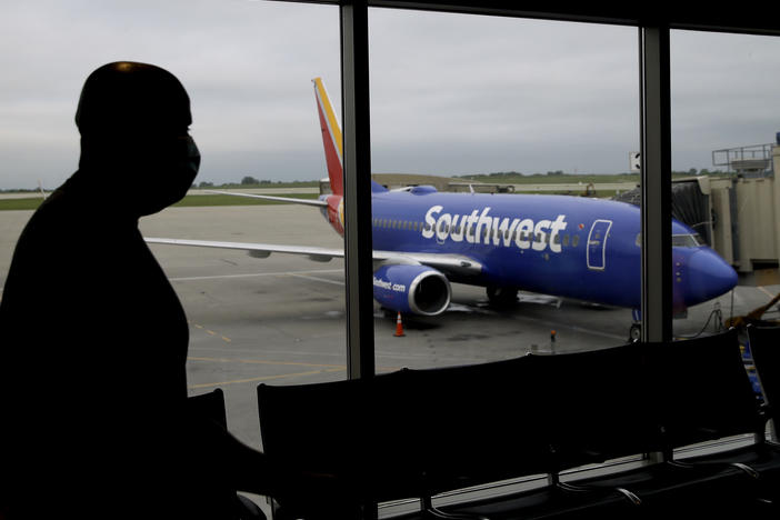 A man wearing a mask prepares to board a Southwest Airlines flight at Kansas City International airport in Kansas City, Mo. Southwest and American Airlines are tightening their mask requirements at the end of July by doing away with exemptions for travelers over the age of 2.