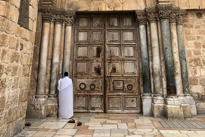 A worshiper prays outside the Church of the Holy Sepulchre, the traditional site of Jesus' tomb. Its wooden doors are shut now to deter the spread of COVID-19, and only clergy may perform the daily prayer rituals inside.