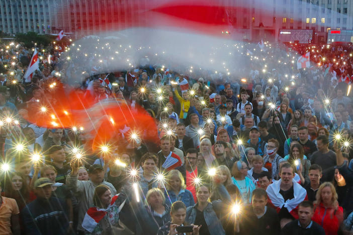 Belarusian opposition supporters turn on phone lights and wave red-and-white flags at a protest in front of the government building at Independence Square in Minsk, on Wednesday.