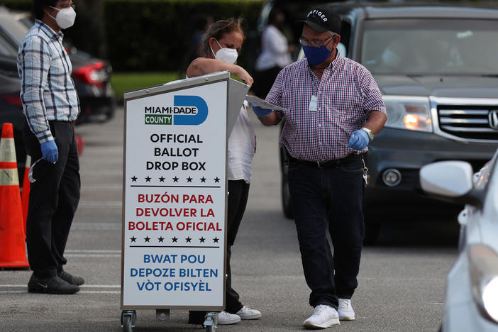 Poll workers at the Miami-Dade County Elections Department deposit returned mail-in ballots into an official ballot drop box on primary election day on Aug. 18 in Doral, Fla.