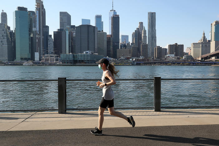 A woman runs with her face mask on Monday in New York City, where the mayor has announced that city personnel will hand out free masks to anyone who is not wearing a face covering.