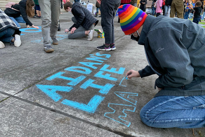 Toren McKnight of Central Point draws on the cement at the vigil for Aidan Ellison outside the Jackson County Courthouse in Medford, Ore., on Dec. 3.