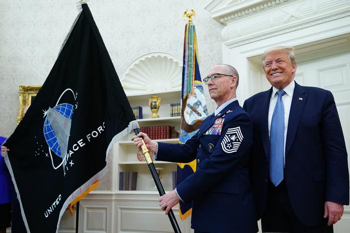 President Trump presedisplays the U.S. Space Force flag in the Oval Office last May. The new command plans to move its headquarters from a temporary location in Colorado to Alabama in 2023.