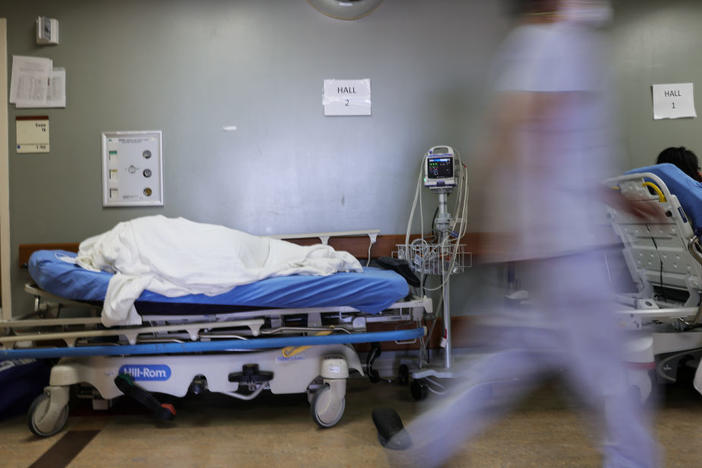 A patient lies on a stretcher in the hallway of the overloaded emergency room at Providence St. Mary Medical Center amid a surge in COVID-19 patients in Southern California in late December. Average new daily infections are now going down in California and much of the country.