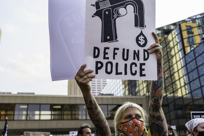 A protester holds a sign reading "Defund the Police" outside Hennepin County Government Plaza during a demonstration against police brutality and racism on Aug. 24, 2020, in Minneapolis.
