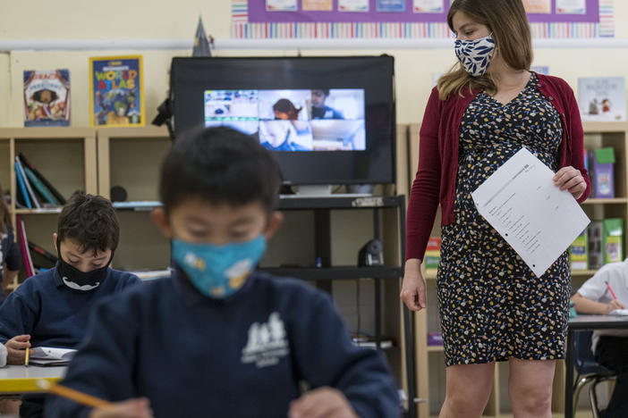 A teacher wearing a protective mask walks around the classroom during a lesson at an elementary school in San Francisco in October 2020.
