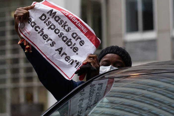 Chicago teachers have voted to accept an agreement for returning to in-person classes in the coming weeks. Here, a woman holds a sign at a car caravan in support of teachers' call for more safety precautions.