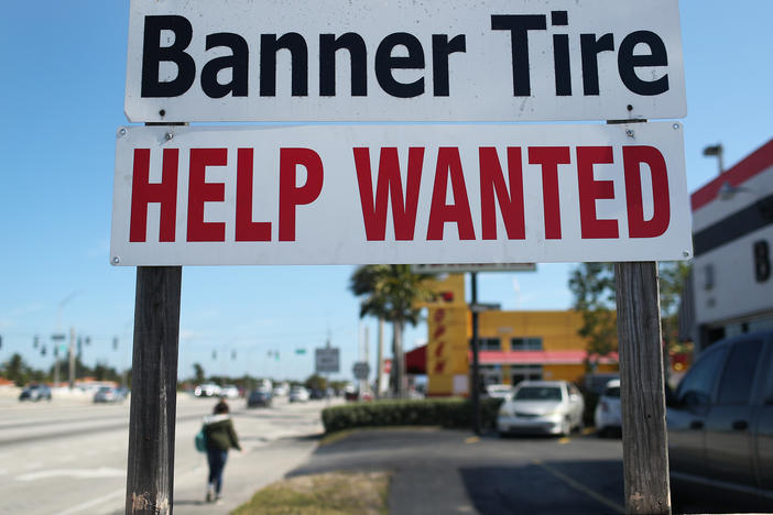 A "Help Wanted" sign is posted in front of a business on Feb. 4 in Miami. Although millions are unemployed, some businesses that require being on-site are struggling to find workers.